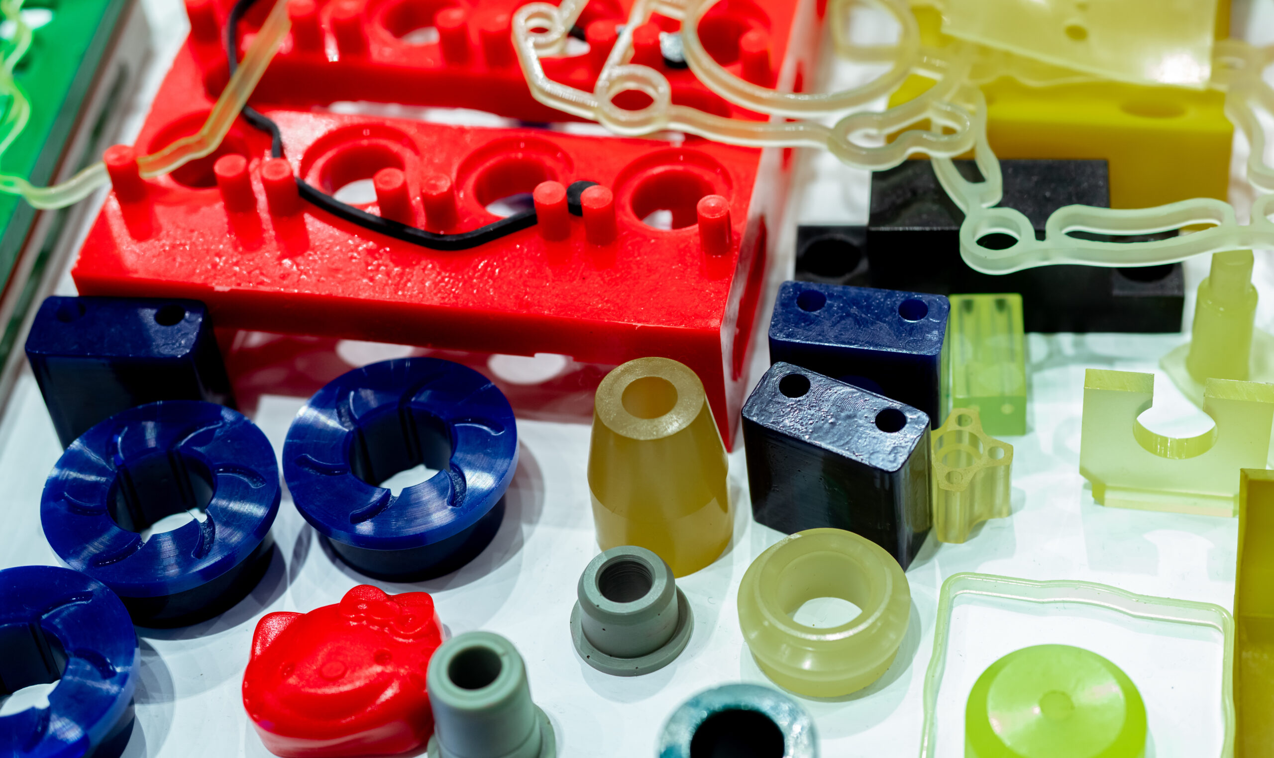 Thermoplastic elastomer (TPE) parts. Thermoplastic polyurethane TPU parts. Santoprene parts. A variety of colorful thermoplastic elastomer (TPE), thermoplastic polyurethane (TPU), and Santoprene parts sitting together on display.